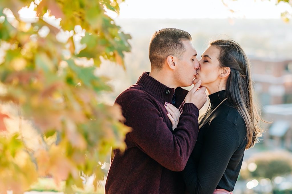 couple kissing next to fall leaves