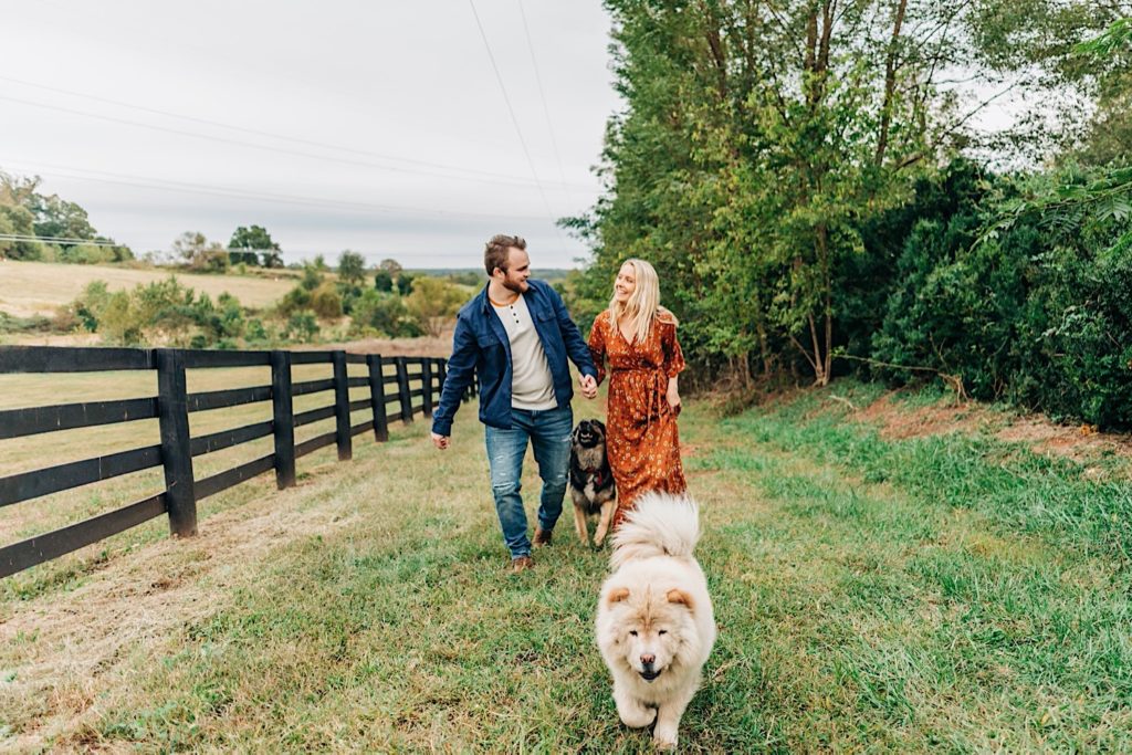 couple walking on a farm with two dogs
