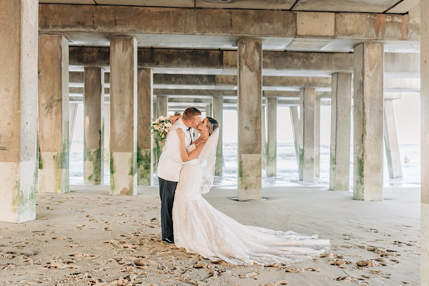 bride and groom kissing under Jennette's Pier