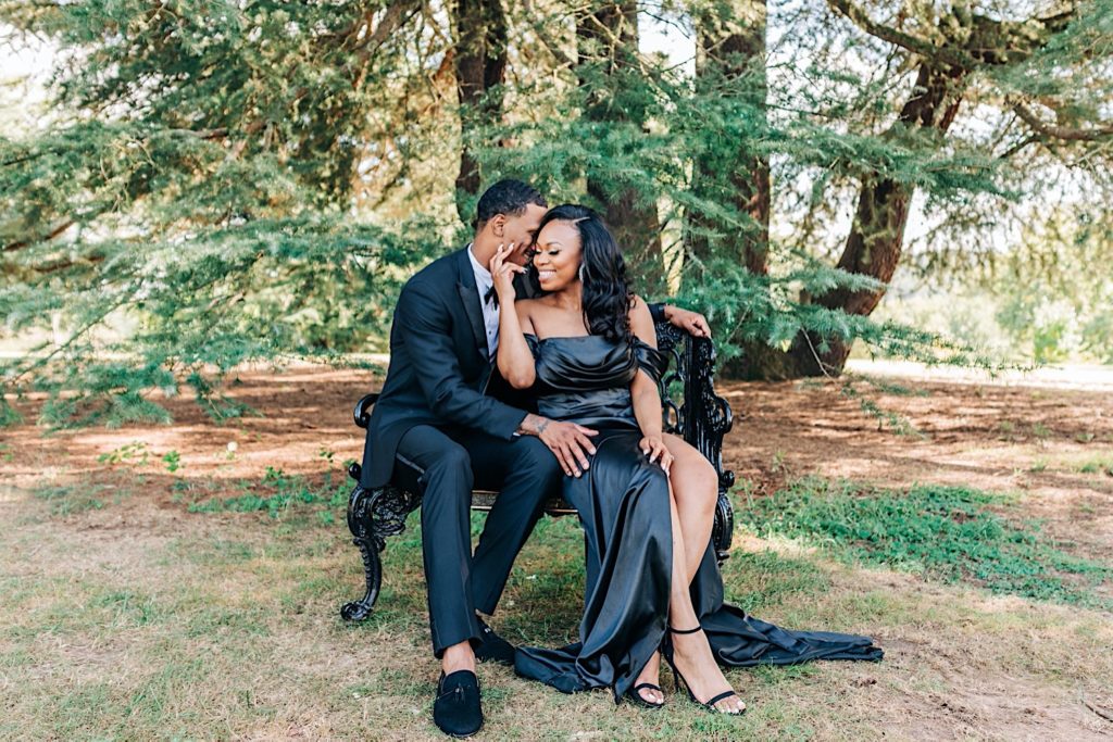couple in all black formal wear snuggling on bench