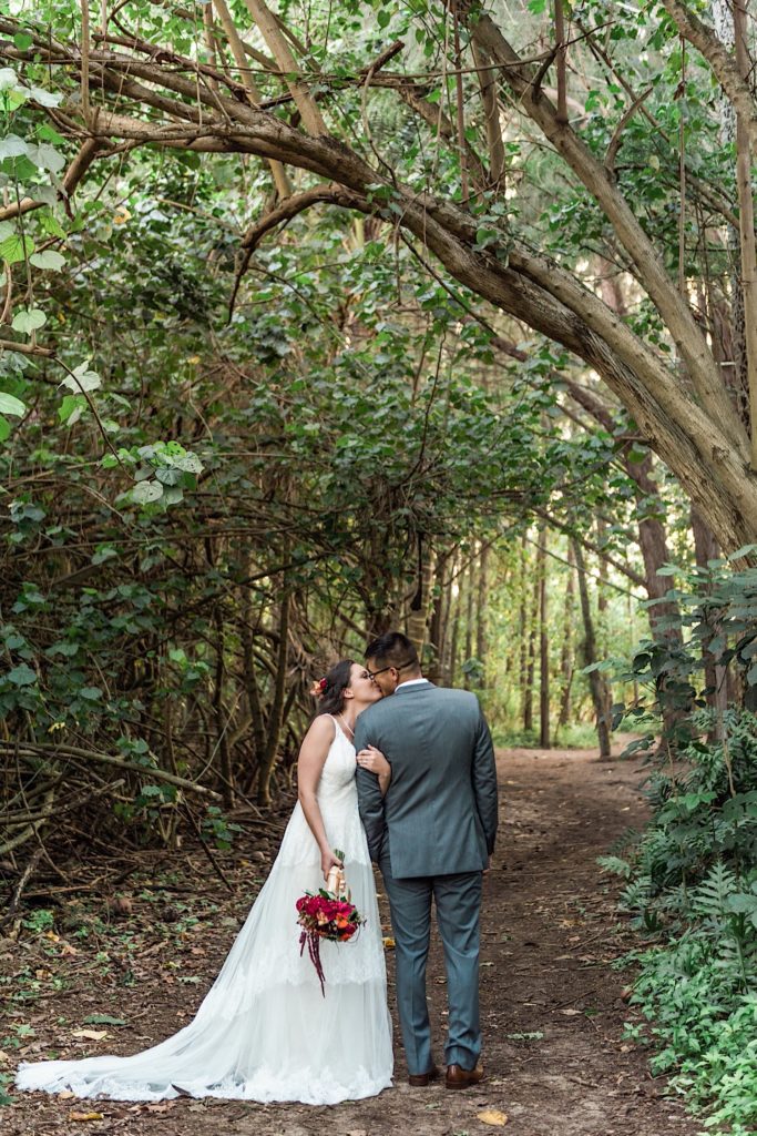 Bride and groom kissing under banyan tree