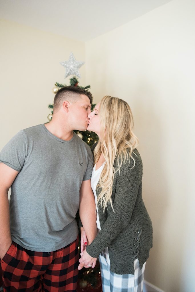 couple kissing in front of the christmas tree
