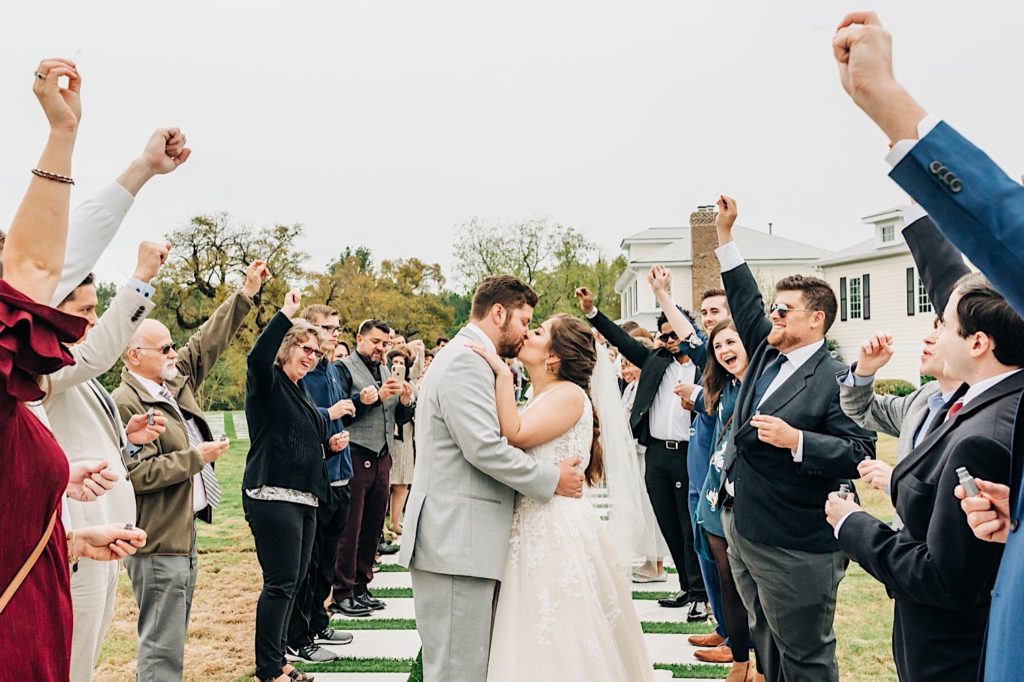 bride and groom kissing while friends cheer