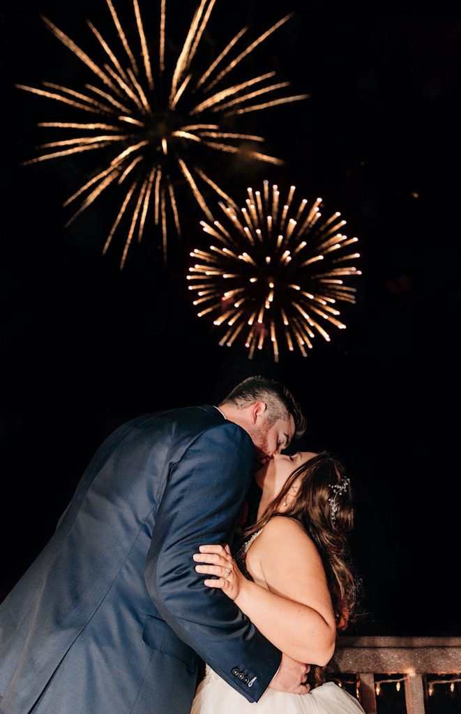 bride and groom kissing during fireworks at welch allyn wedding