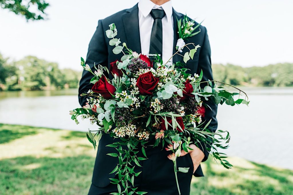 groom next to the water in Virginia with bouquet