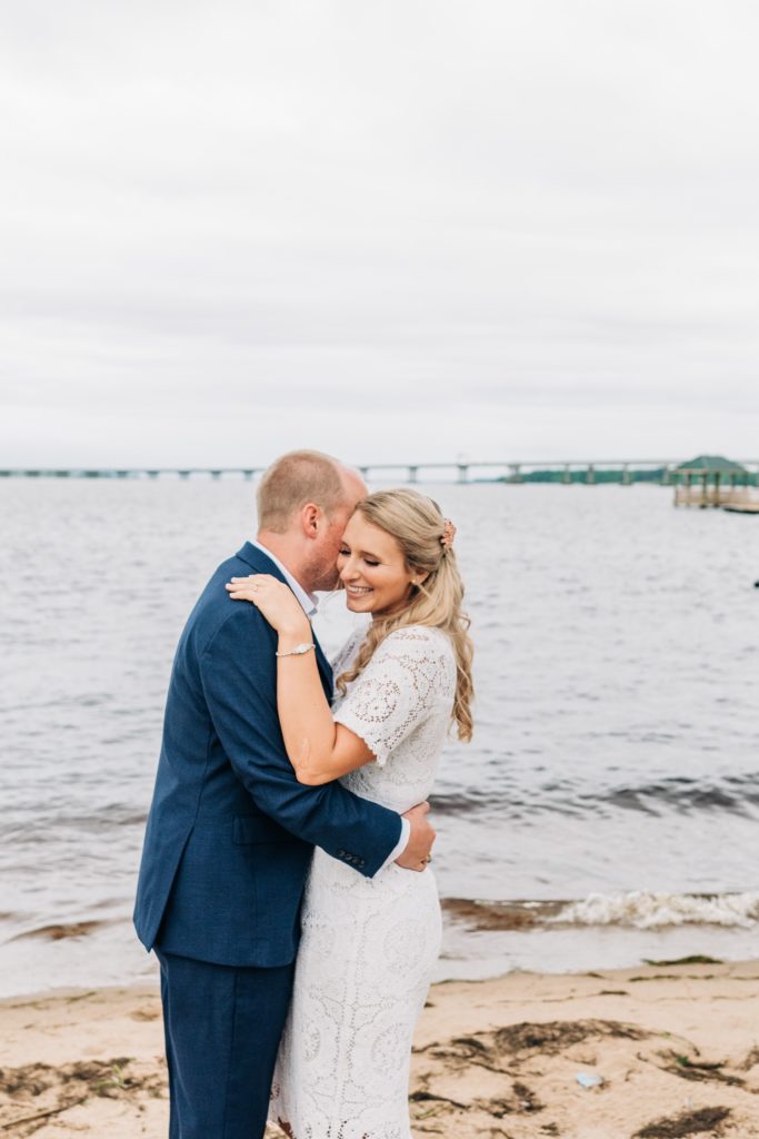 Bride and groom snuggling next to the water in New Bern NC