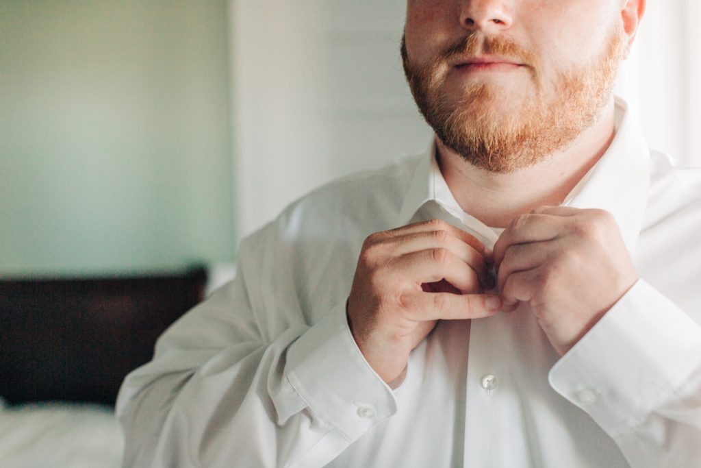 groom buttoning shirt at wild horse estate