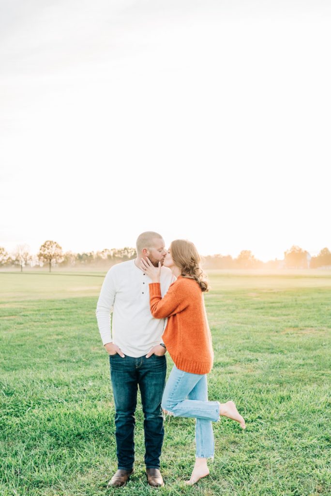 a couple kissing in a field at sunset