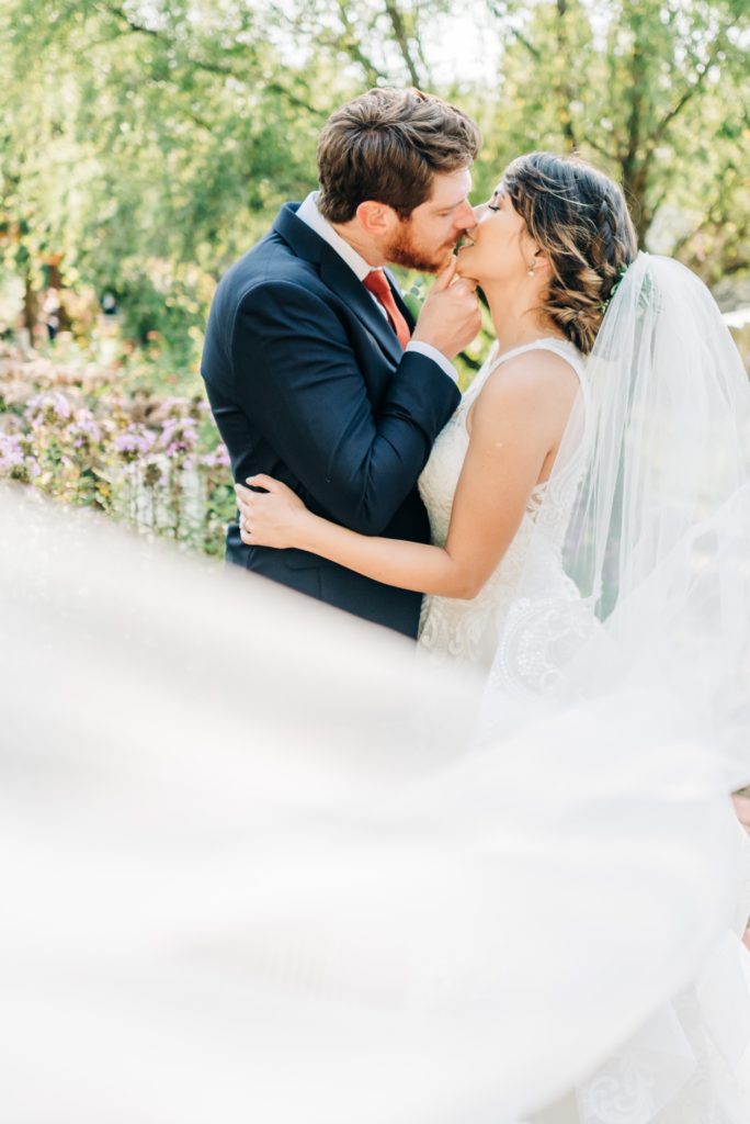 bride and groom kissing with veil in the garden at Clay Hill