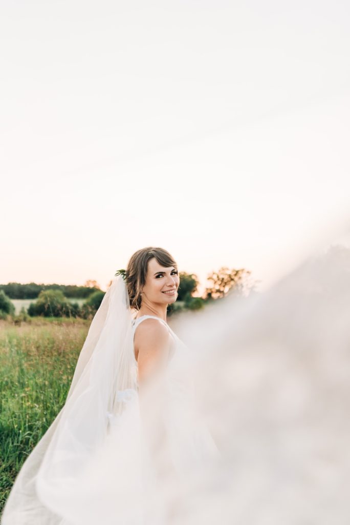 bride with veil at sunset in a field