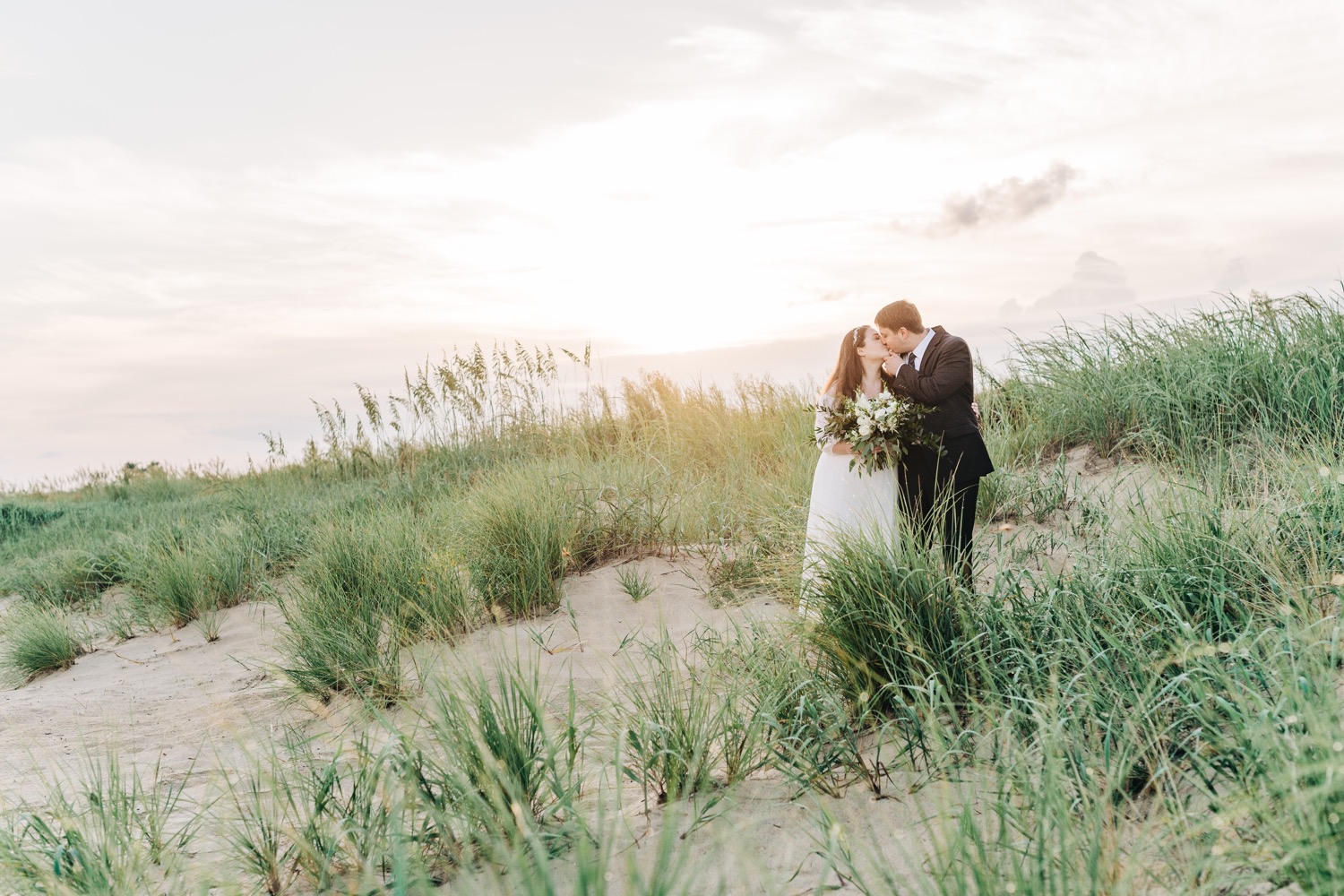 Bride and groom kissing at sunrise beach elopement