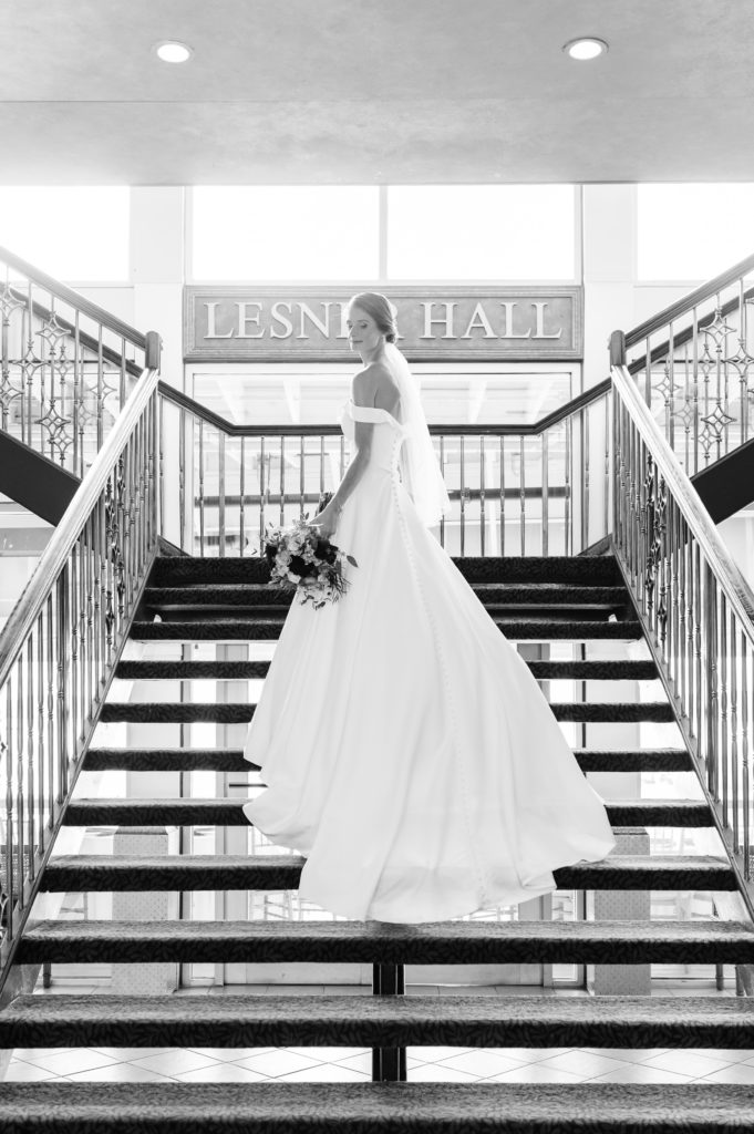 Bride in a blusher veil posing on a staircase with her bouquet of flowers