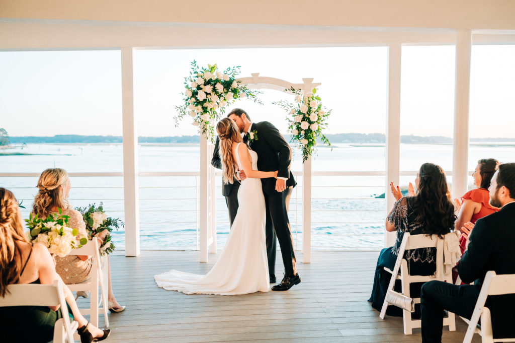 Bride and groom kissing at the altar by the water