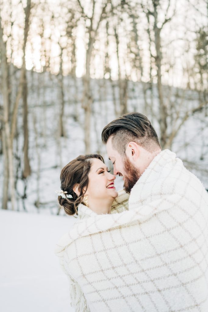 bride and groom snuggling in the snow