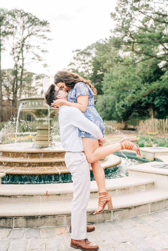 Groom lifting up the bride in front of the fountain for engagement photos