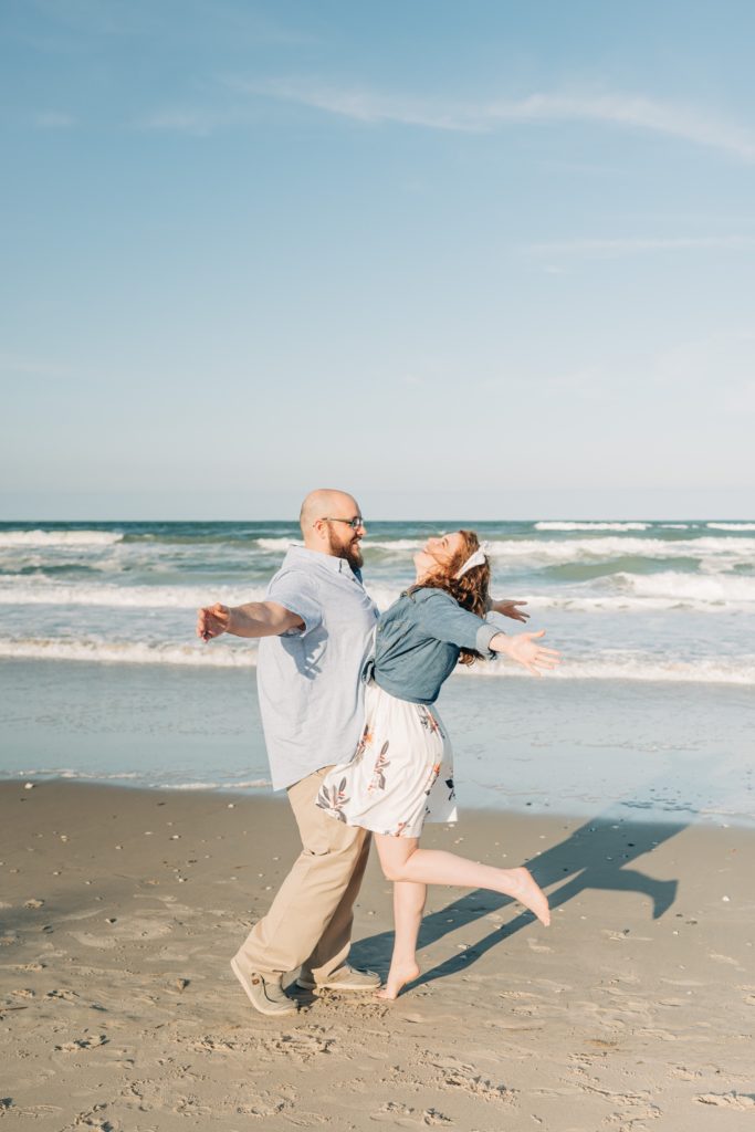 Couple belly bumping on the beach in Corolla, NC for engagement portraits