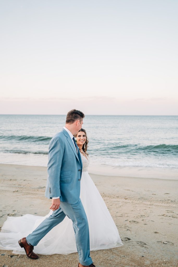 Bride and groom walking hand in hand down beach on their wedding day