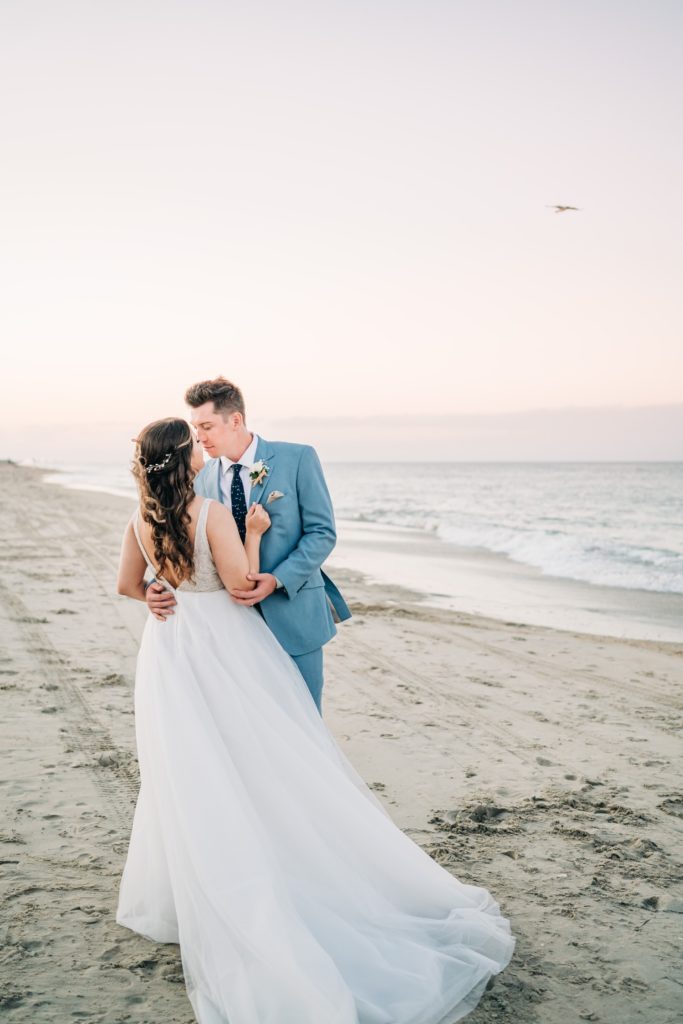 Bride and groom embracing on beach in Outer Banks, NC