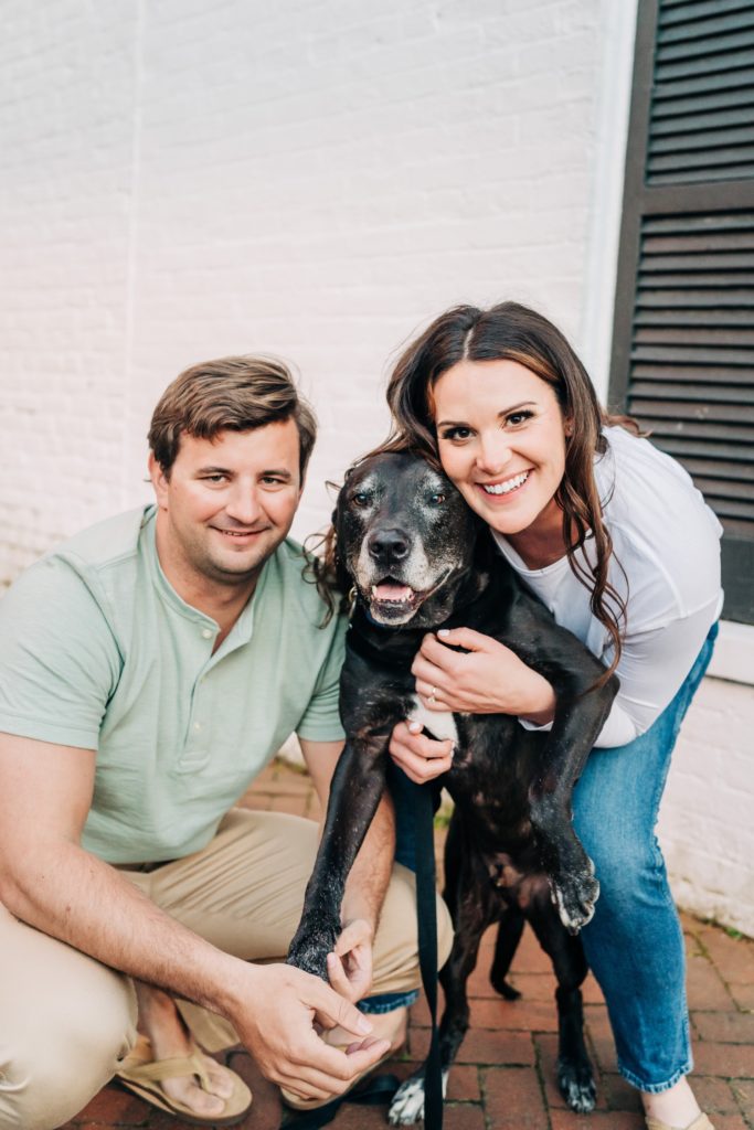 Couple posing and smiling with their dog.