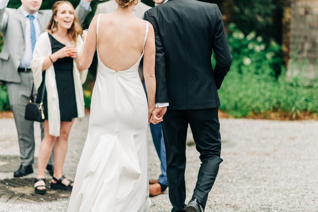 Photo of bride and groom from behind holding hands