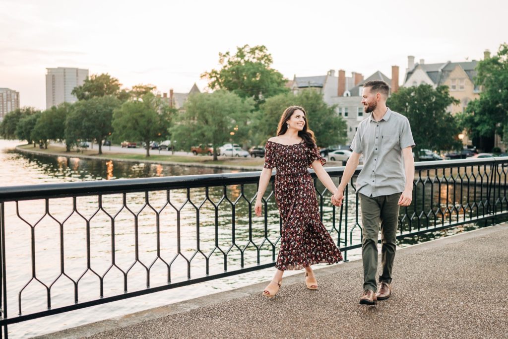 Engaged couple walking over bridge hand in hand for Norfolk VA engagement portraits