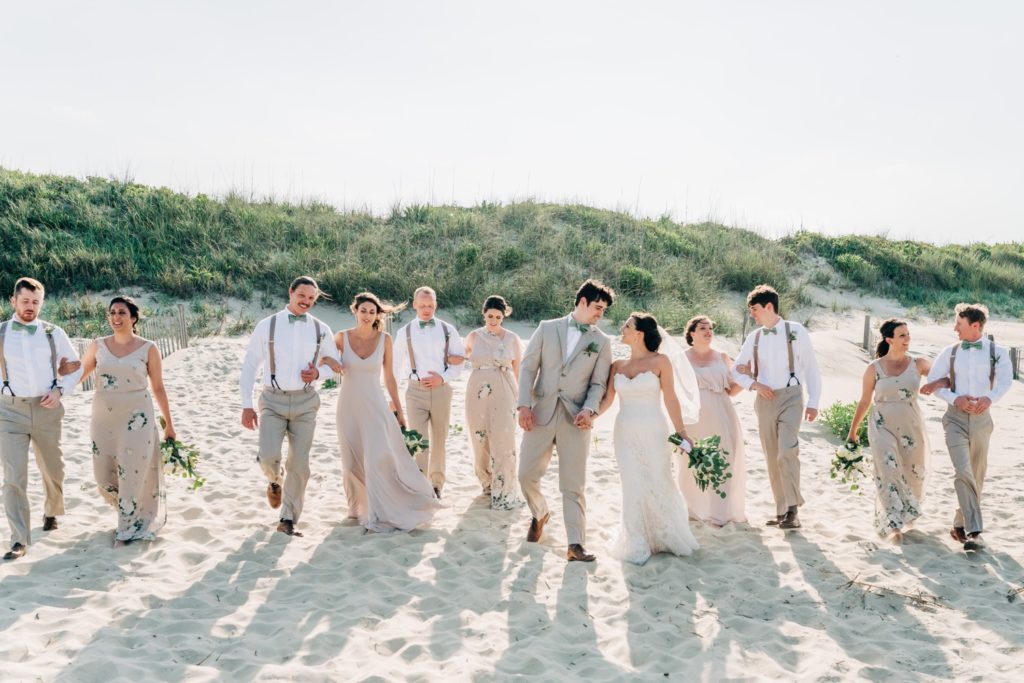 Bridal party walking with bride and groom on the beach in Duck NC