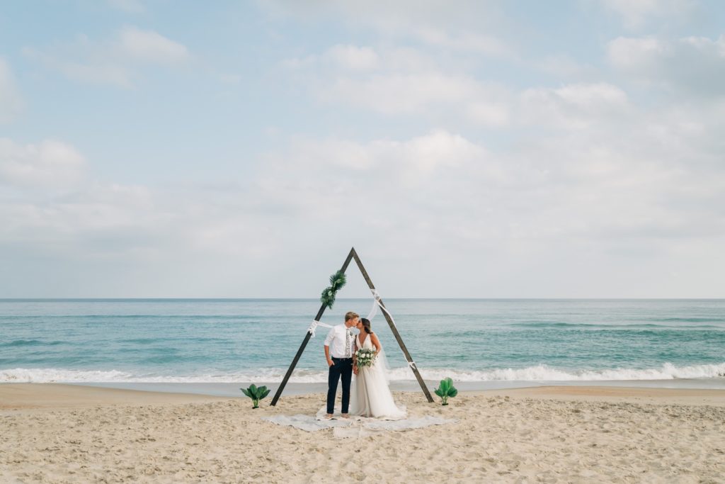 Bride and groom kissing with the ocean in the background at Hatteras OBX wedding