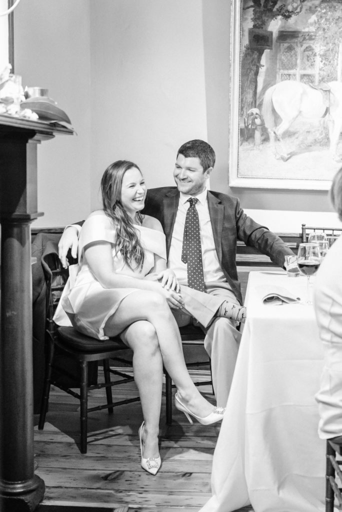 bride and groom at rehearsal dinner during toast laughing