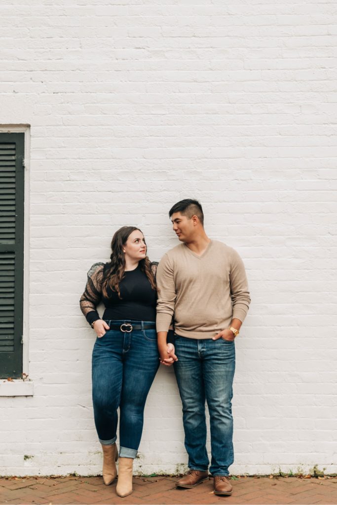 couple holding hands leaning against wall