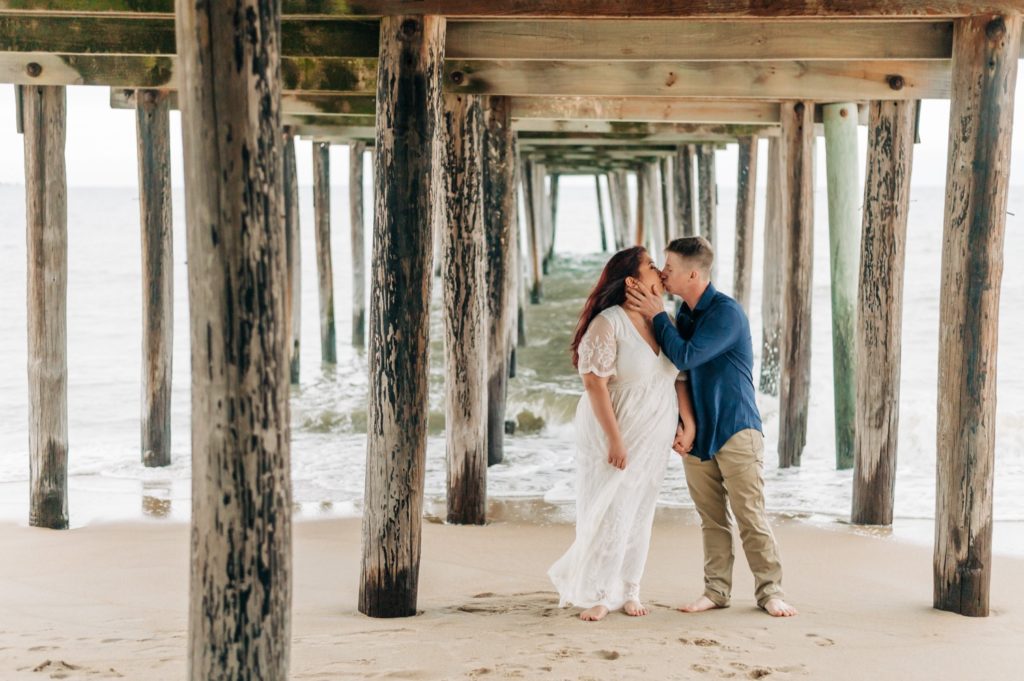 couple kissing under pier for Virginia Beach Engagement Portraits
