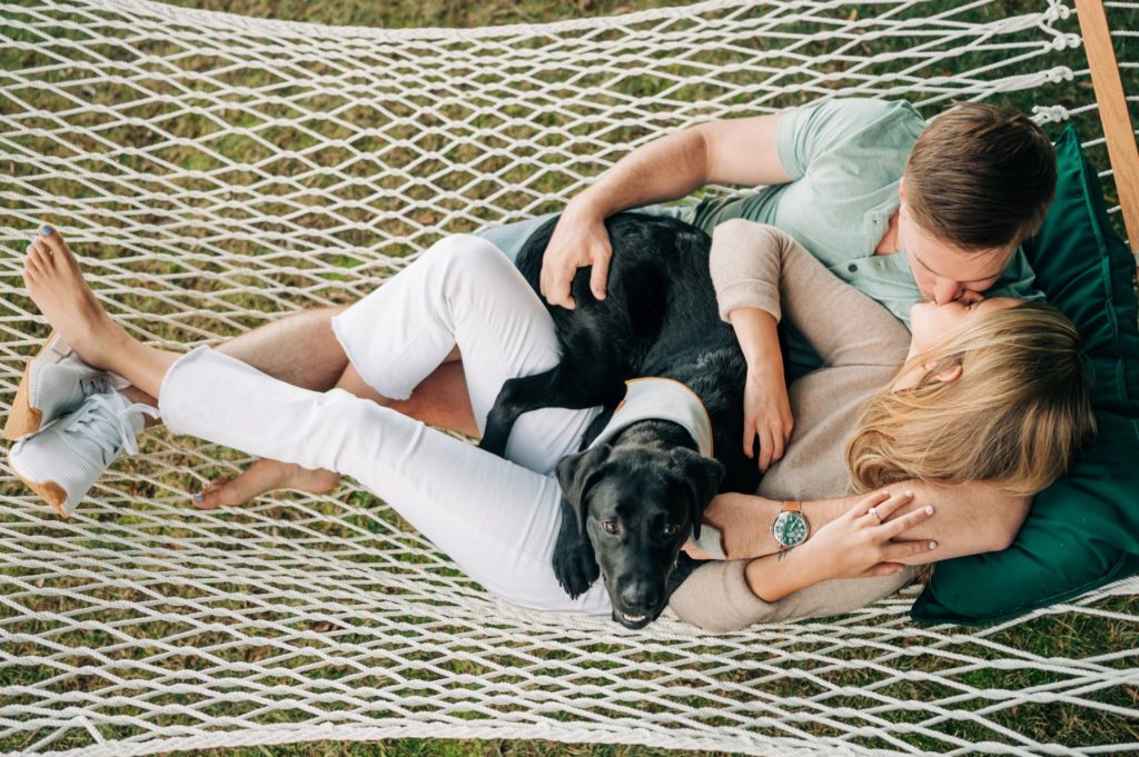 couple kissing in hammock with black lab puppy