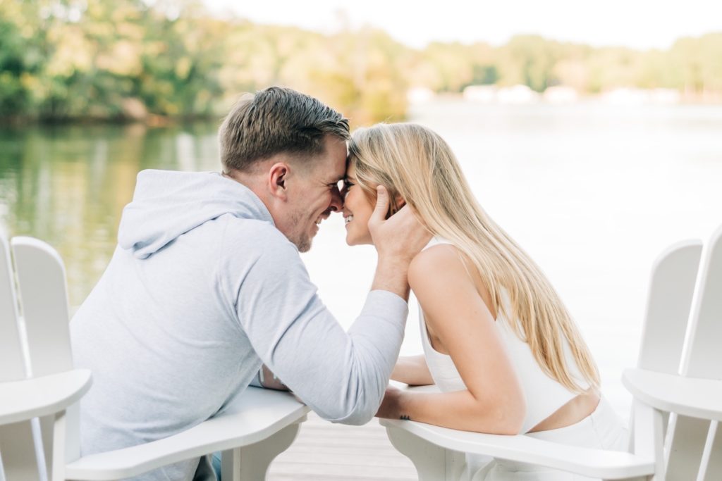 a couple going in for a kiss while sitting on a dock on lake Anna
