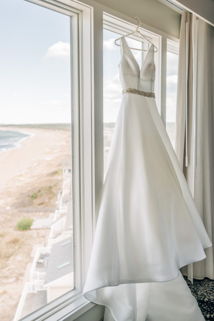 bride's dress hanging infront of beach
