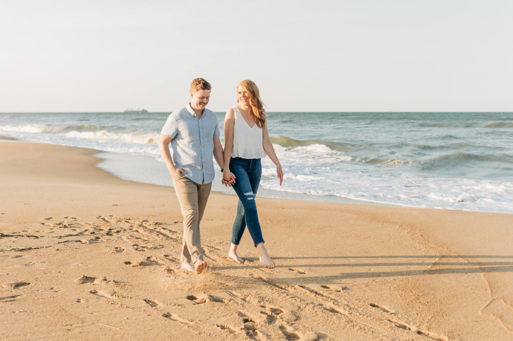 Engaged couple walking along the beach in Virginia Beach for their first landing park engagement portraits 
