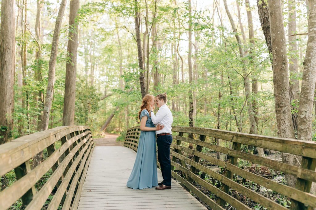 couple in blue on a bridge in a Virginia state park looking and caressing each other. 