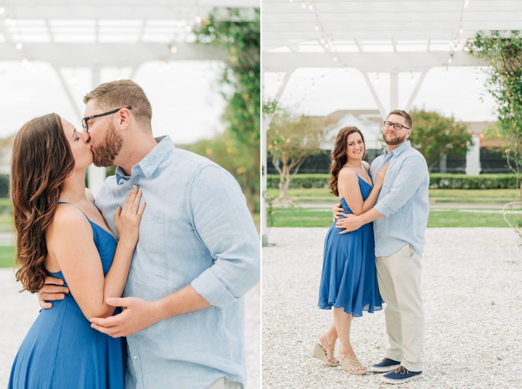 Couple wearing matching blue outfits kissing in front of beach buildings. Engaged couple hugging and looking at the camera while smiling 