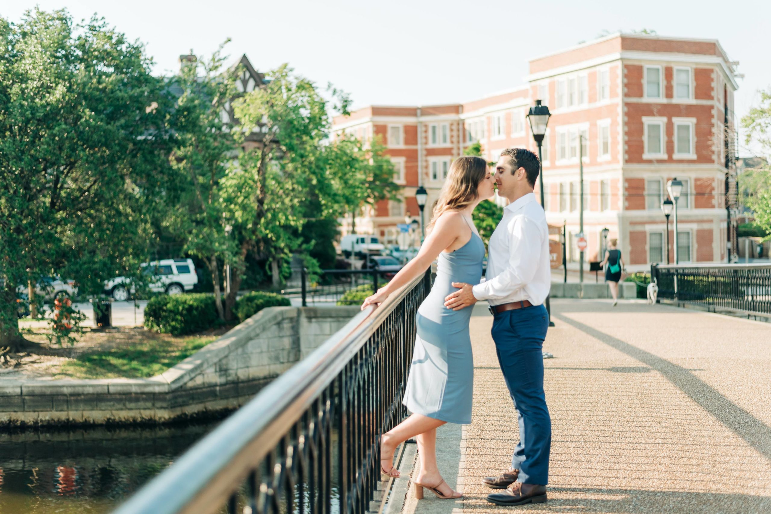 engaged couple in blue dress kissing on the bridge in Norfolk Virginia