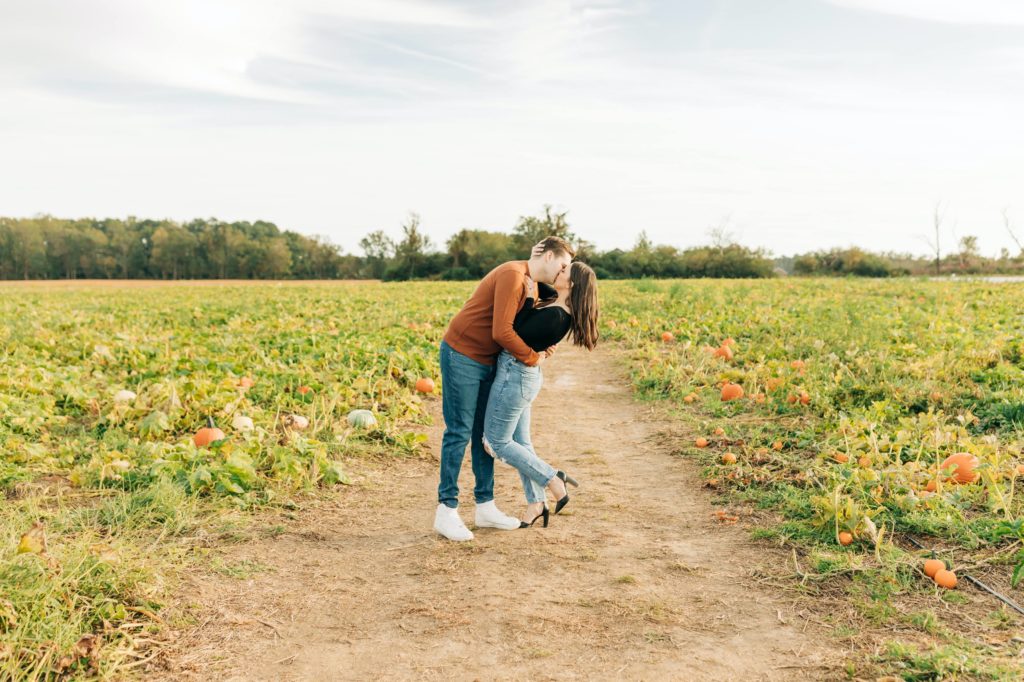 Engaged couple kissing in the middle of a pumpkin patch for their Cullipher Farm engagement