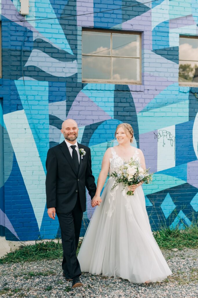 bride and groom smiling in front of blue Richmond mural