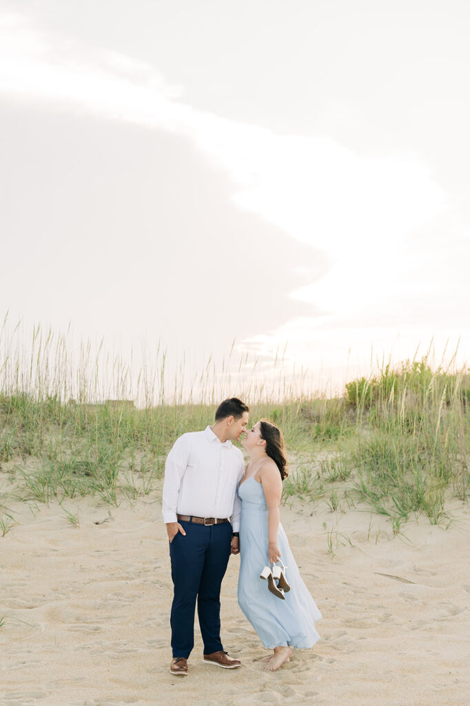 Couple leaning in for a kiss in Virginia Beach by the dunes.