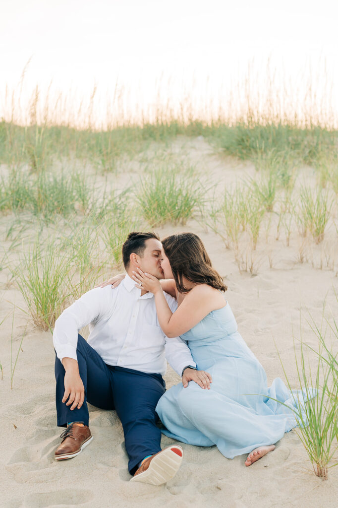 Couple sitting and kissing on the sand in Virginia Beach