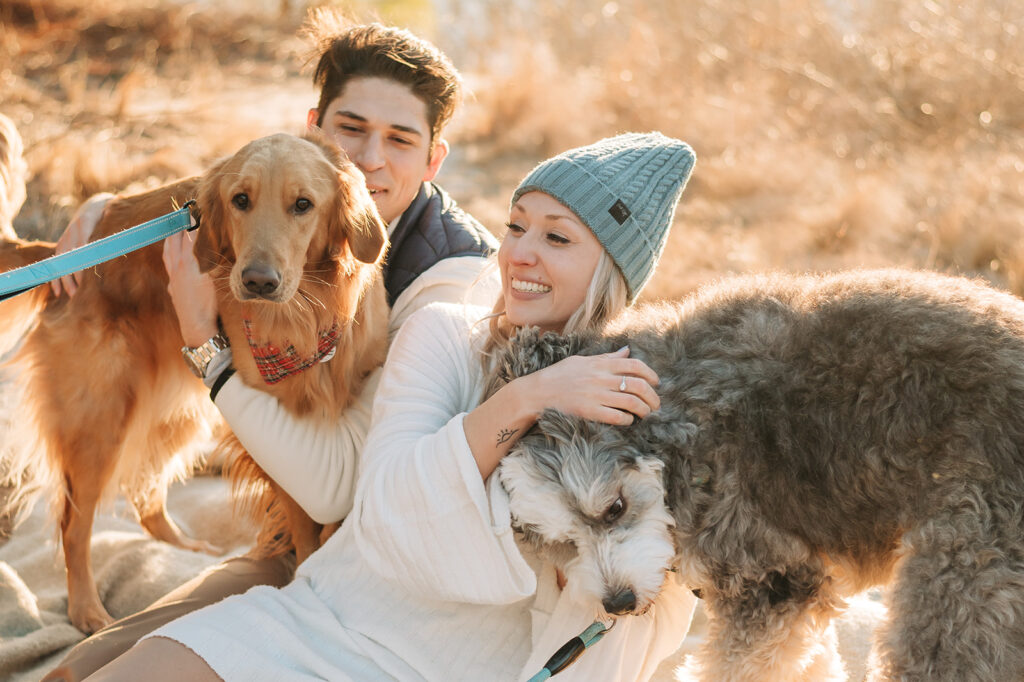 couple laughing with their dogs on the beach