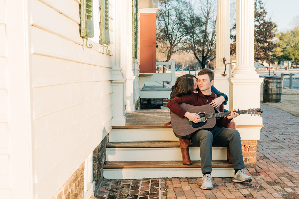 girl kissing boy on cheek while playing guitar