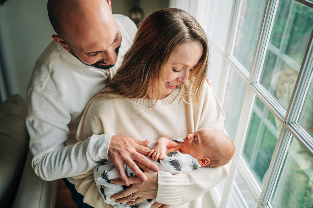 mom and dad smile at baby