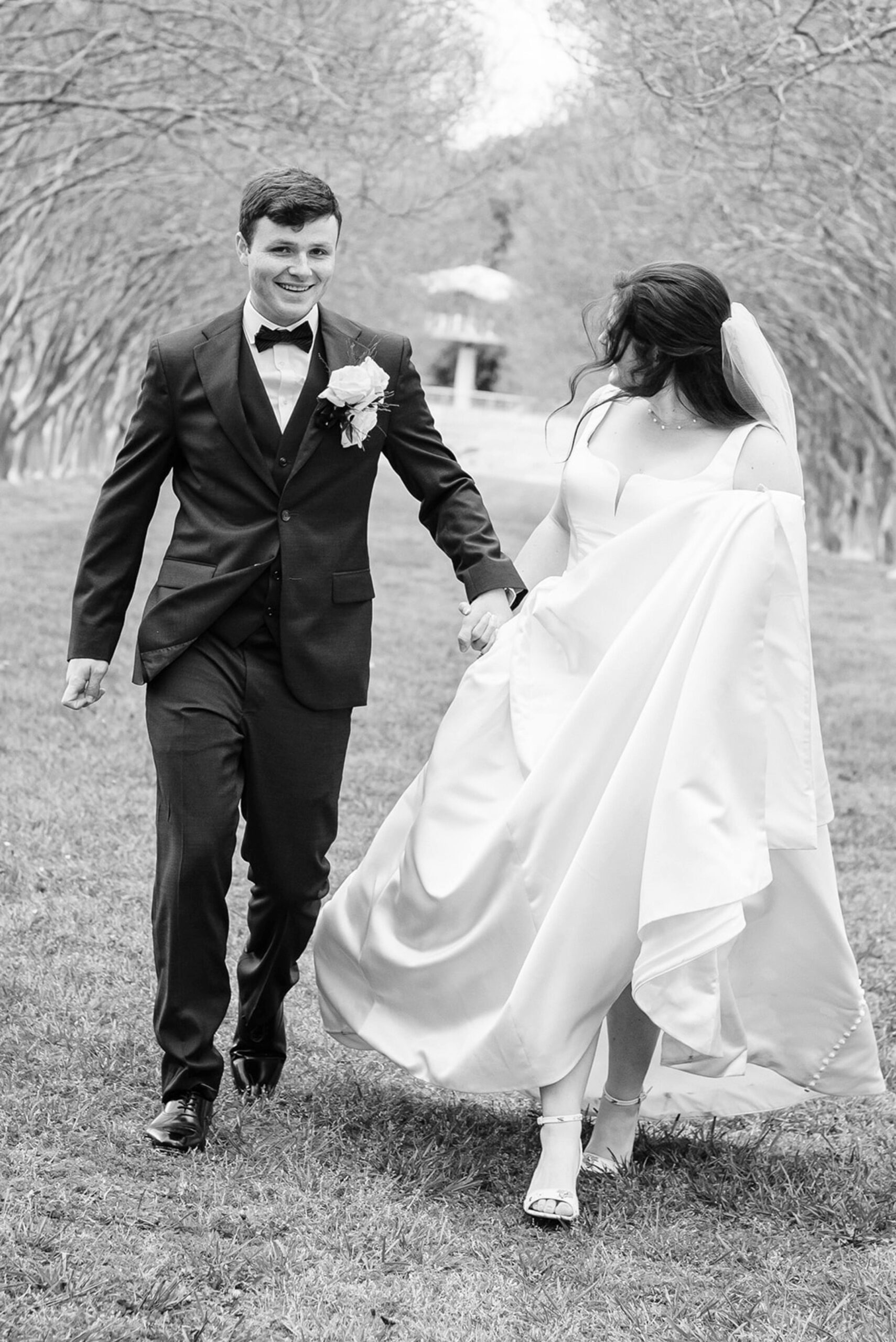 black and white photo of bride and groom running