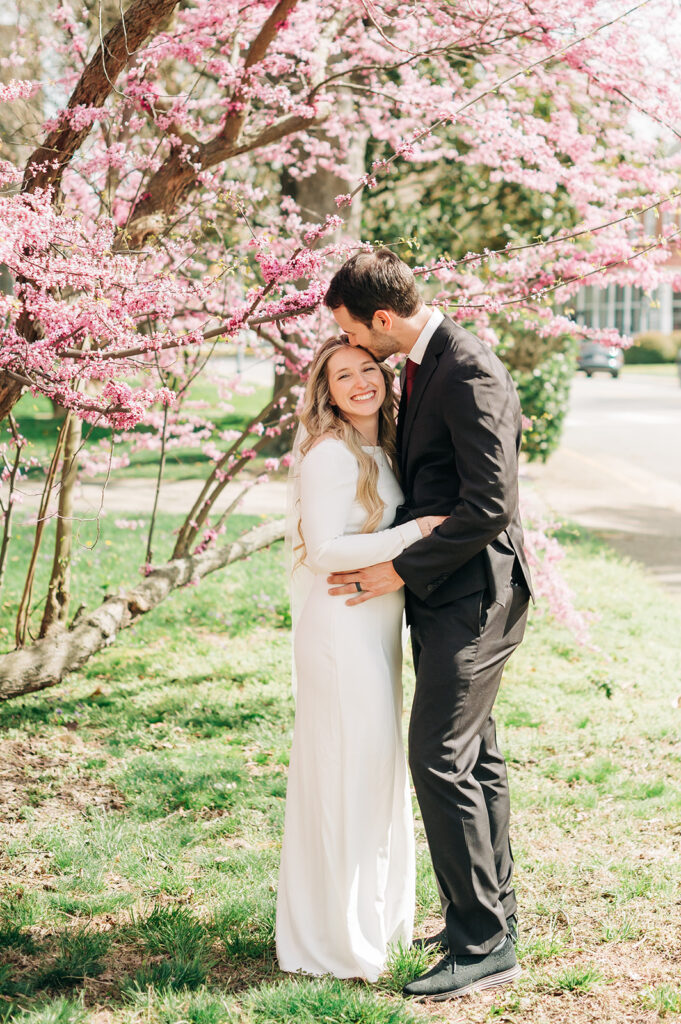 couple kisses under pink flowers