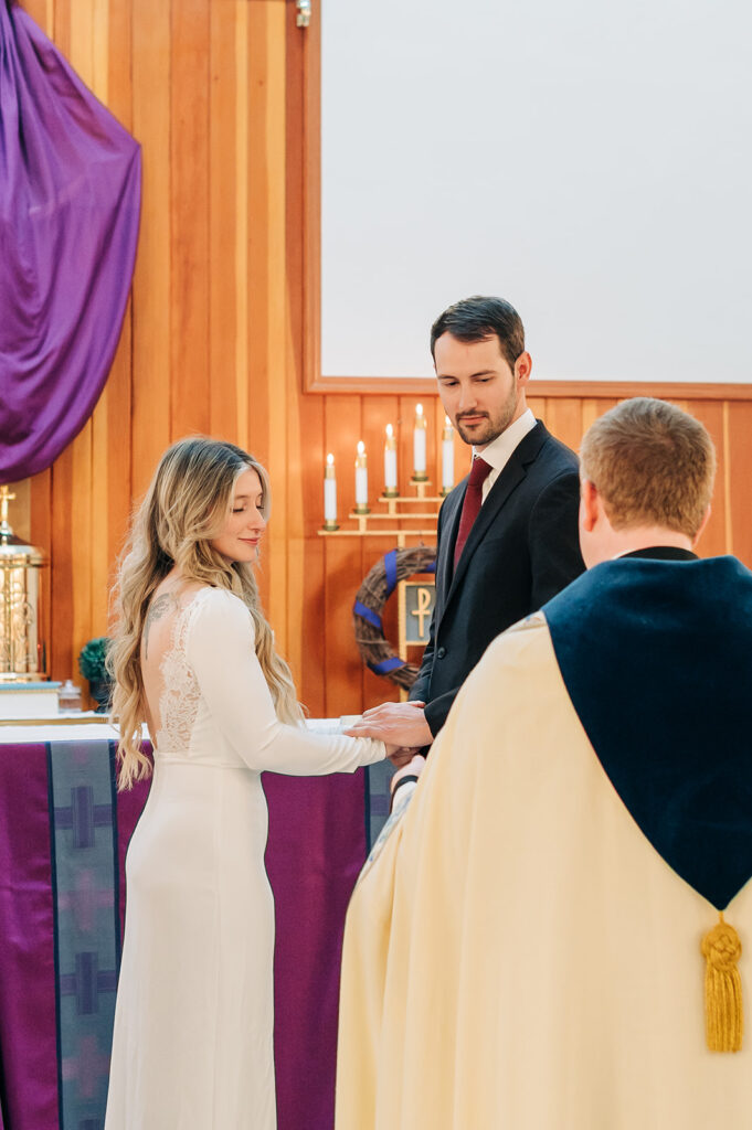couple holds hands at alter