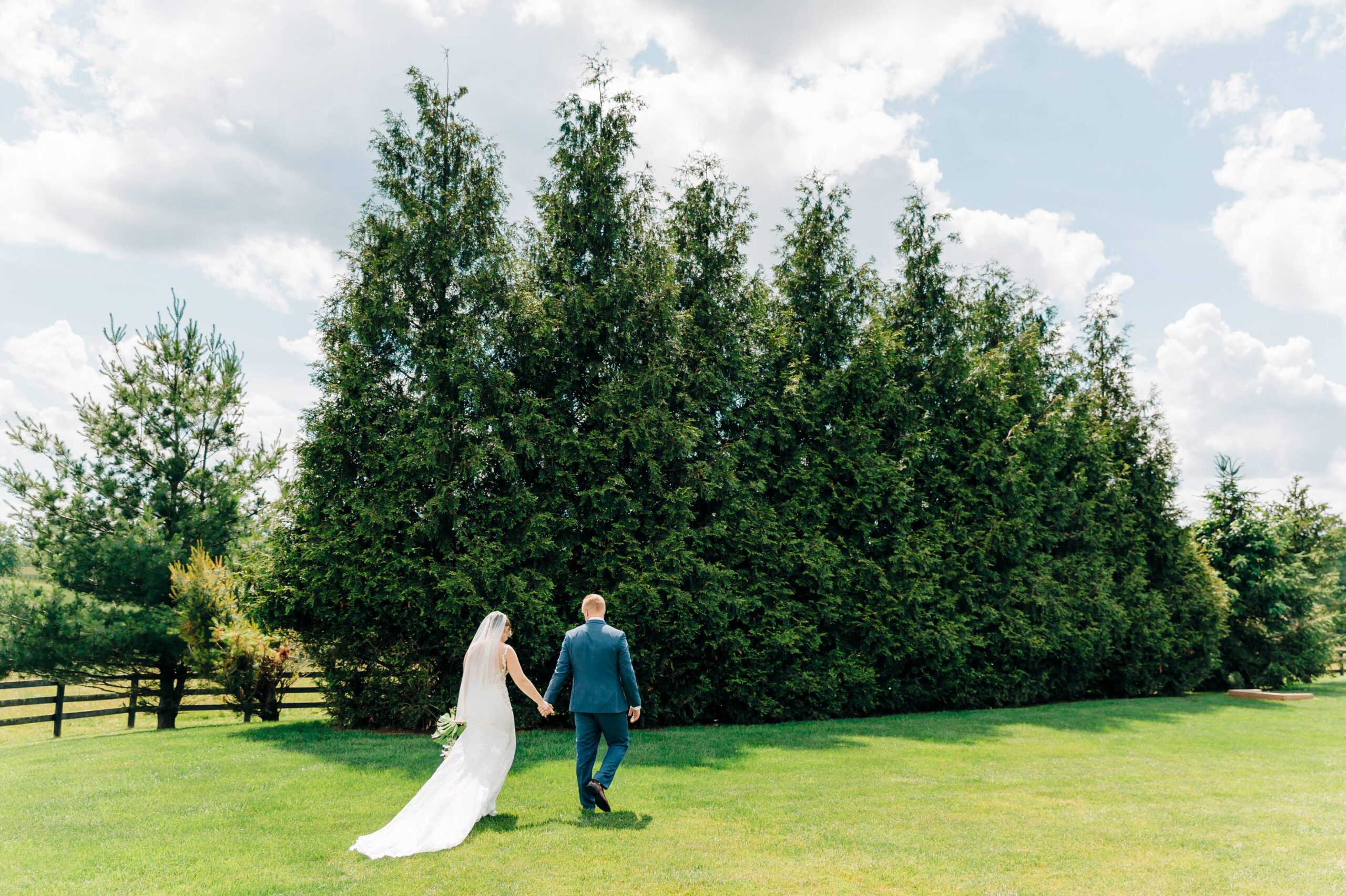 bride and groom walk in field
