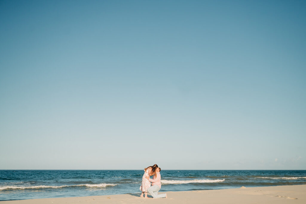 couple kisses on beach after proposal